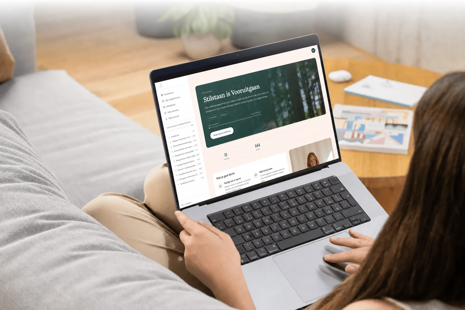 Laptop met een module van het online programma, naast een werkboek en een kop thee